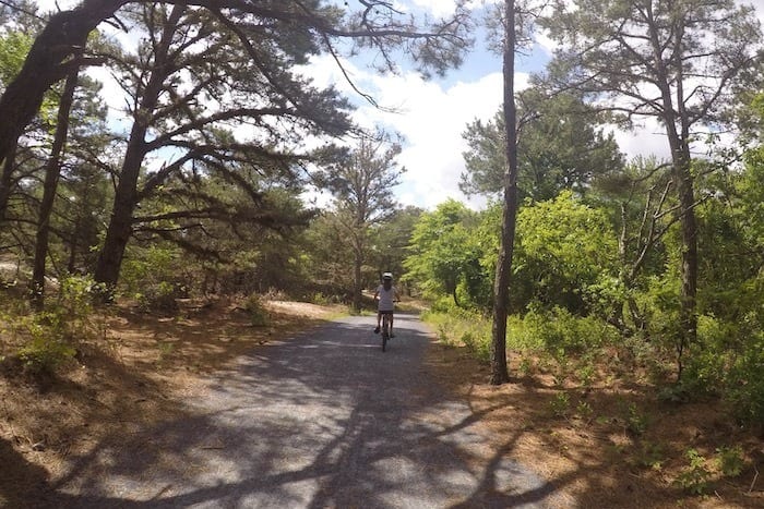 girl biking on path through the woods