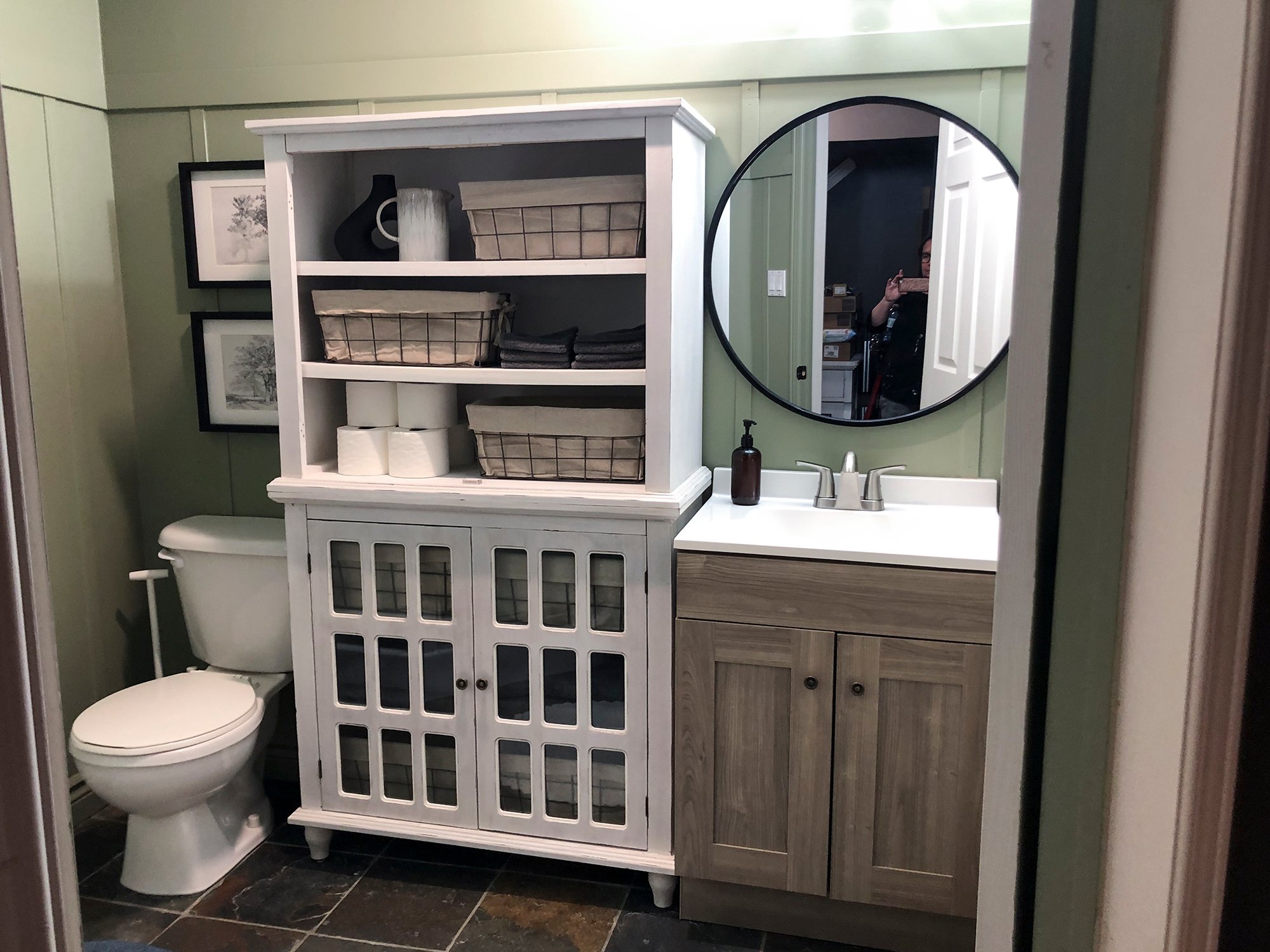 green bathroom with board and batten on walls, white hutch for storage and grey vanity
