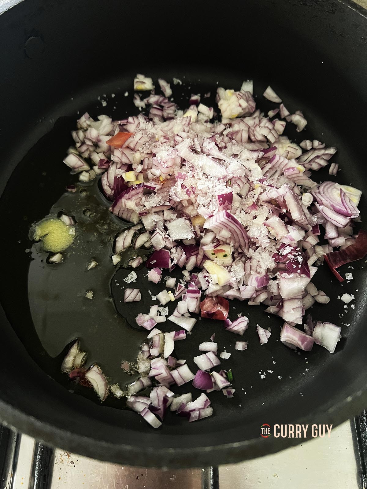 Melting the niter kebbeh in a large pan and adding the chopped onions along with about 1/2 tsp salt.