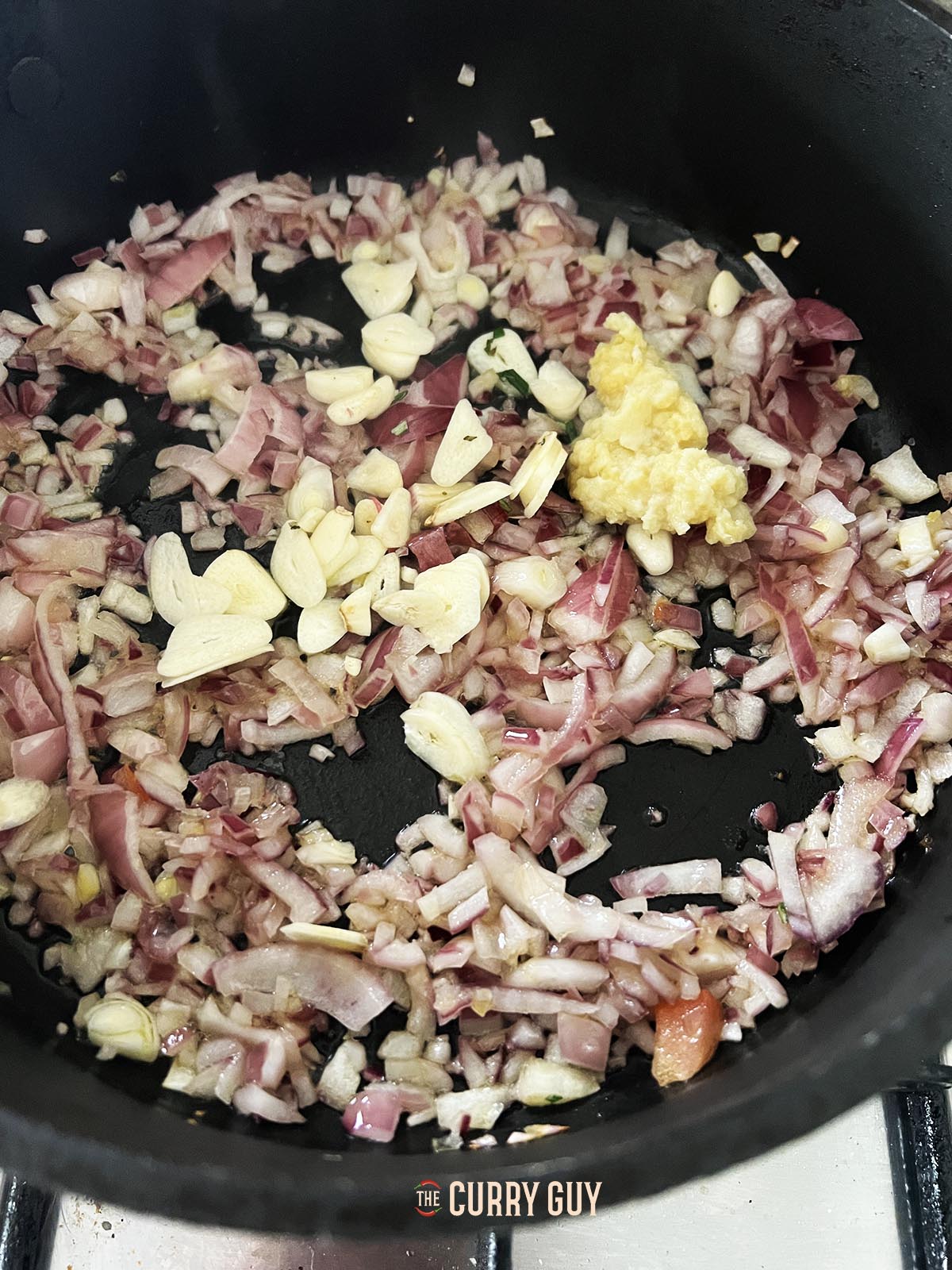 Frying the chopped onions until soft in a pan and then adding garlic and ginger paste and sliced garlic cloves.
