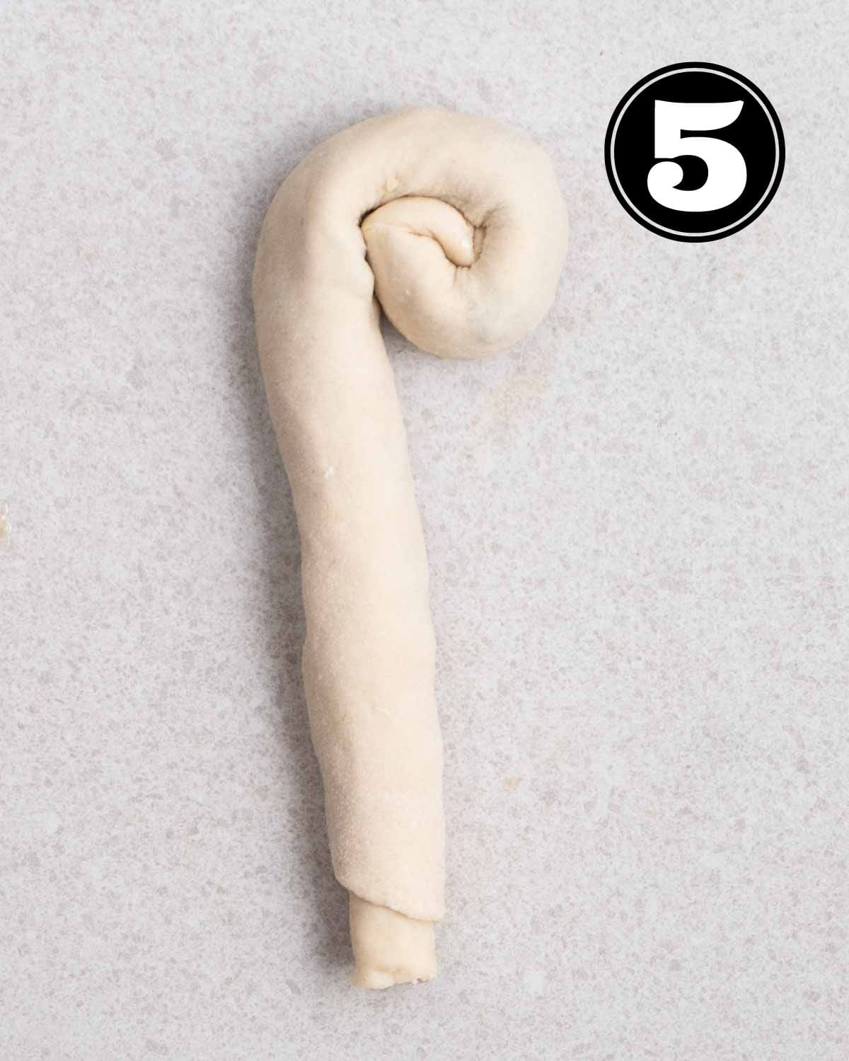 A partially rolled up rope of scallion dough.