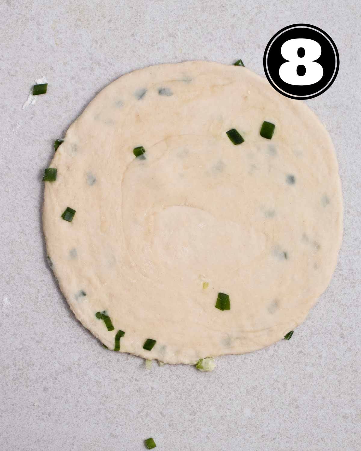A piece of uncooked shaped scallion pancakes.