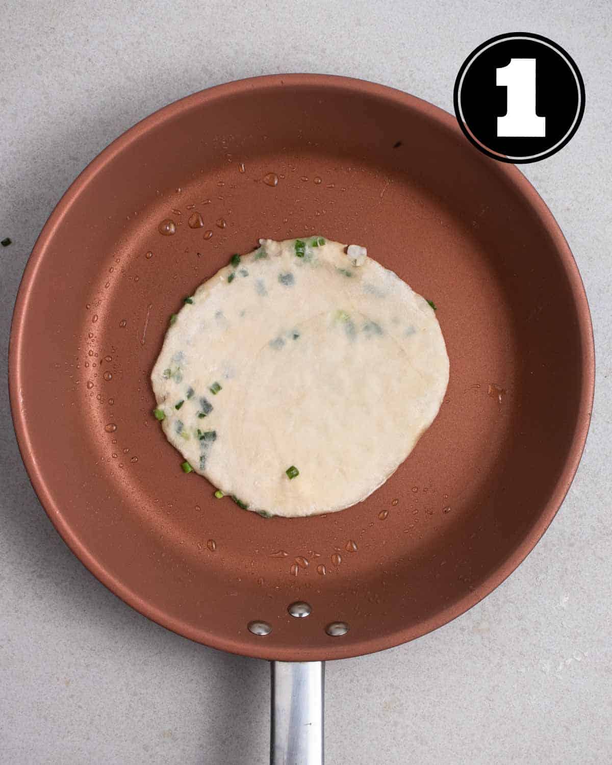 Cooking a scallion pancake in a non-stick pan.