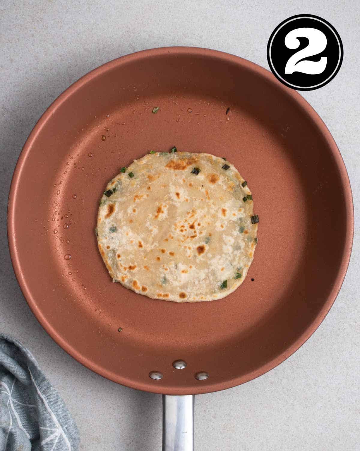 Cooked scallion pancake in a non-stick pan.