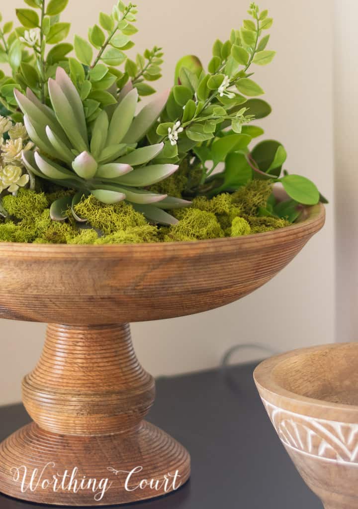 wooden pedestal bowl filled with green moss and faux succulents